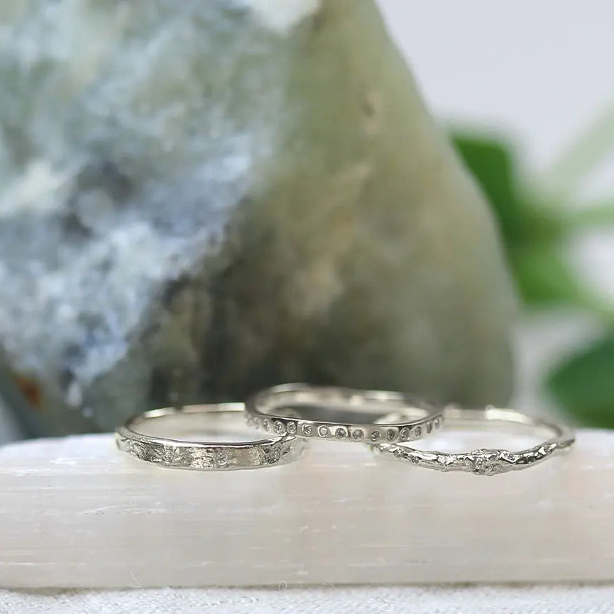 Three Platinum wedding rings on a white stone with a natural background