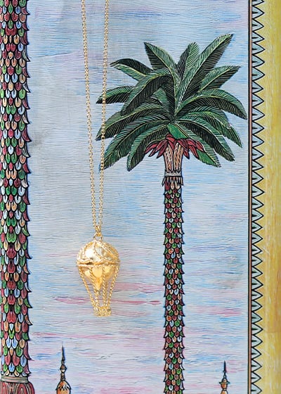 Hot-air balloon necklace on a summer palm tree backdrop